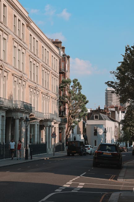The image shows a quiet residential street in Kennington with tall, ornate terraced houses featuring light-colored facades, decorative window surrounds, and small balconies. Several large cardboard bo